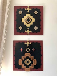 two pieces of art hanging on a wall